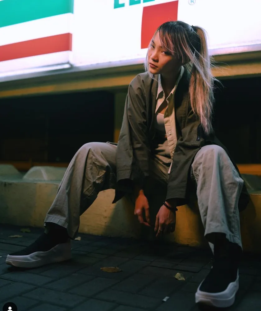 Model sitting on a curb wearing the third prototype
